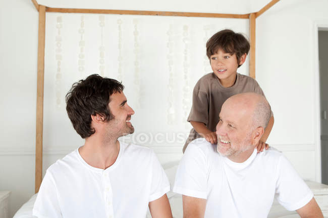 Three generations of men on bed — Stock Photo