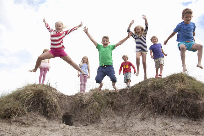 Groupe d'enfants sautant des dunes de sable, Pays de Galles, Royaume-Uni — Photo de stock
