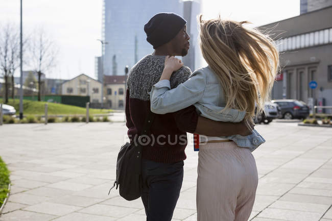 Multi ethnic couple hugging in street — Stock Photo