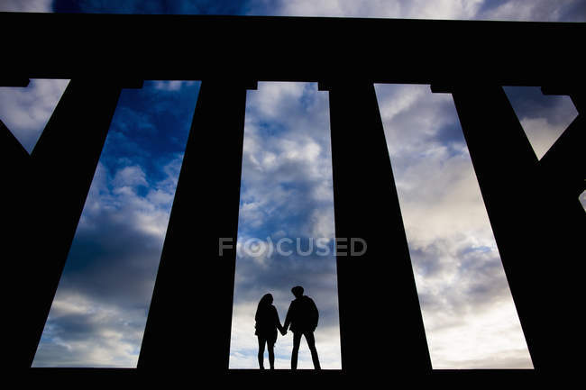 A young couple hold hands at the National Monument on Calton Hill in Edinburgh, Scotland — Stock Photo