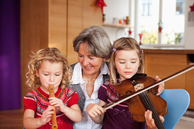 Abuela enseñando música a nietos - foto de stock