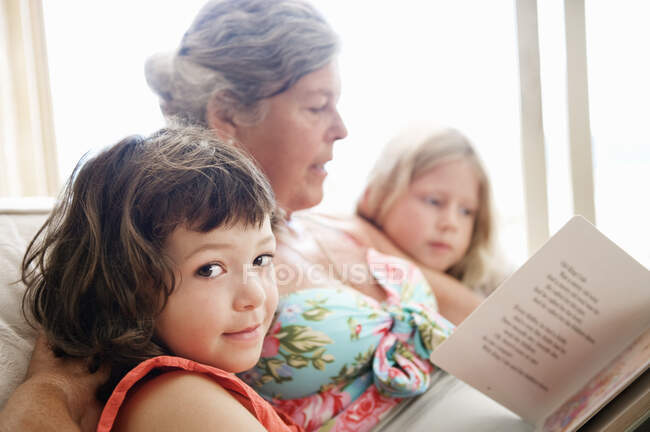 Пожилая женщина читает некоторым детям — стоковое фото