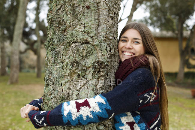 Jeune femme étreignant arbre dans la forêt — Photo de stock