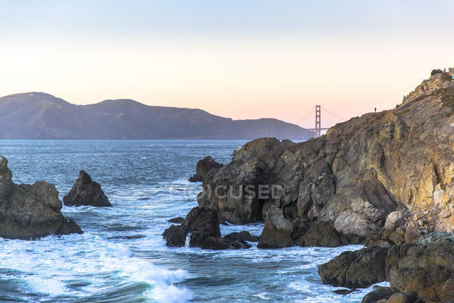 Rocky shore with mountain range and Golden Gate bridge — Stock Photo