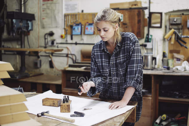 Junge Handwerkerin überprüft Bauteile auf Werkbank in Pfeifenorgelwerkstatt — Stockfoto