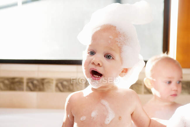 Baby boy covered in soap suds in bath — Stock Photo