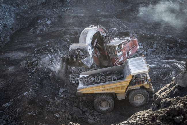 Excavator and dumper truck in void at surface coal mine — Stock Photo
