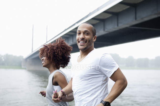 Молодая пара бегает по мосту, Дюссельдорф, Германия — стоковое фото