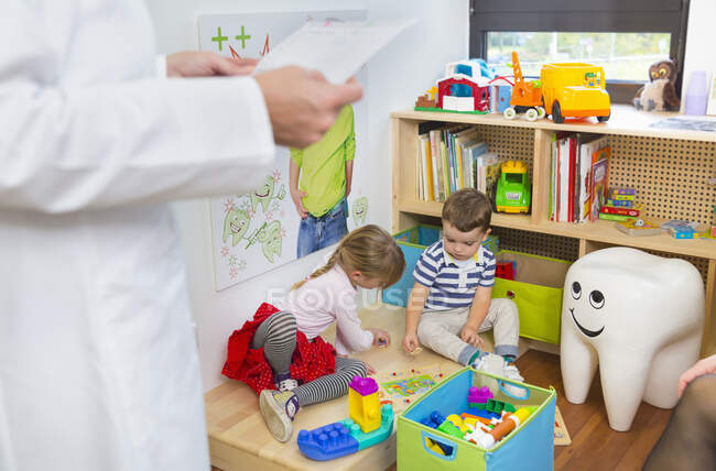 Children playing on floor, dentist in foreground — Stock Photo