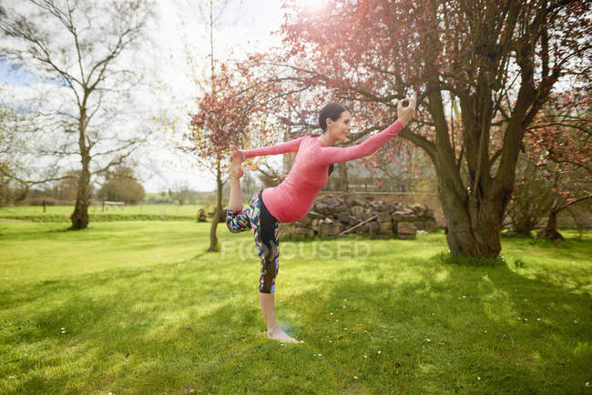 Mujer embarazada al aire libre, en posición de yoga - foto de stock