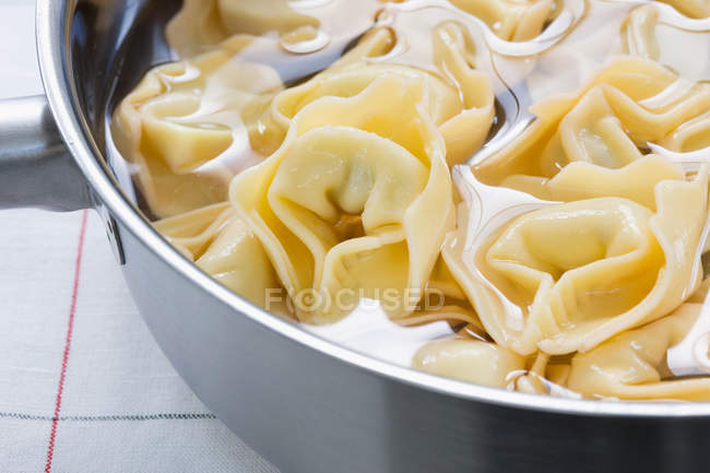 Meat dumplings and water in saucepan at kitchen counter — Stock Photo