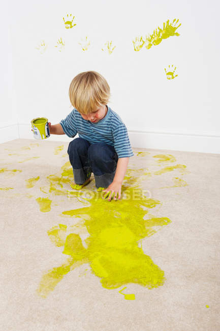 Мальчик выплескивает краску на ковер — стоковое фото