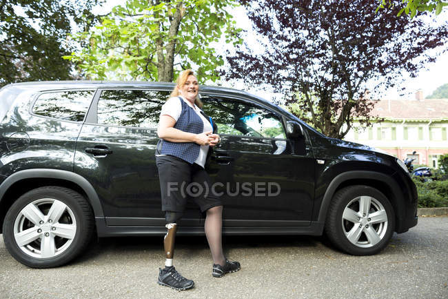 Ritratto di donna adulta con gamba protesica, in piedi accanto all'auto — Foto stock