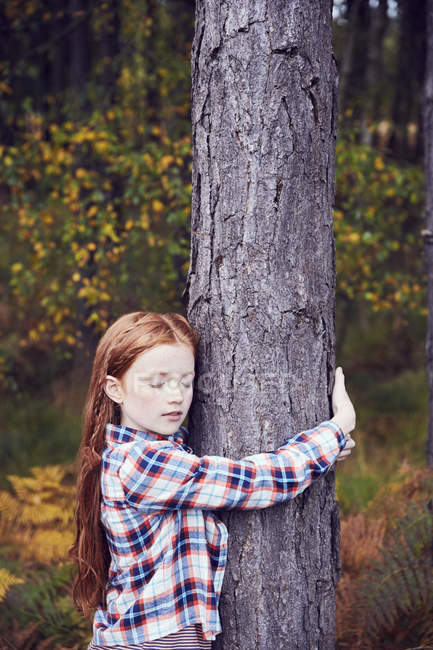 Jovencita, abrazando el árbol - foto de stock