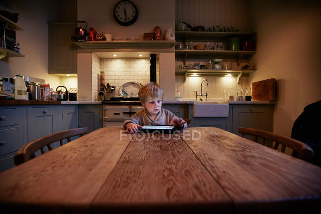 Хлопчик використовує планшетний комп'ютер за столом — стокове фото