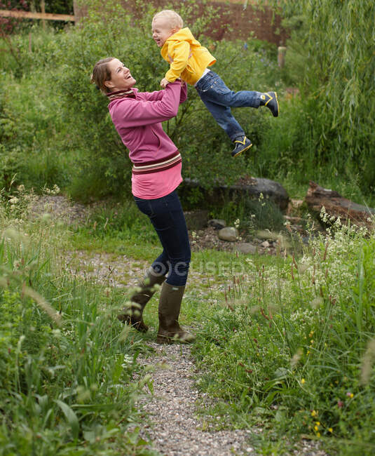 Mãe balançando filho no quintal — Fotografia de Stock