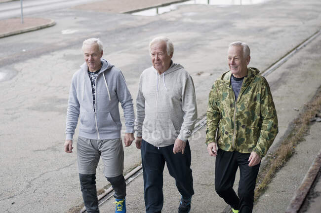 Amici anziani che indossano vestiti sportivi che camminano fianco a fianco — Foto stock