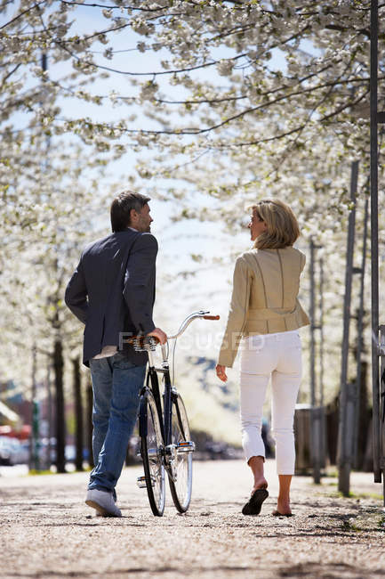 Couple walking bicycle in park — Stock Photo