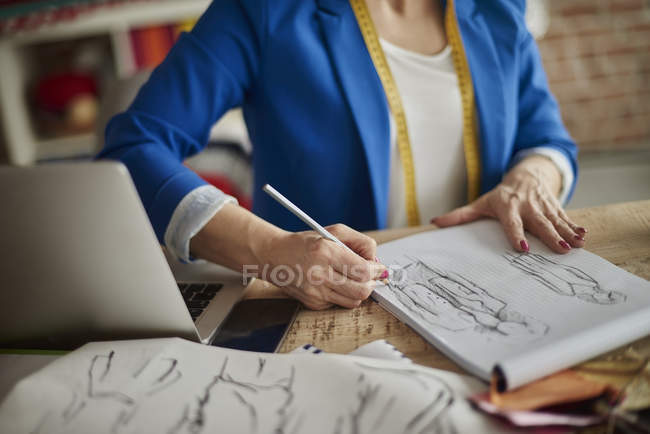 Abgeschnittene Ansicht einer Frau, die am Schreibtisch sitzt und Modedesign skizziert — Stockfoto