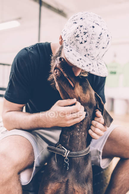 Young male hipster petting dog — Stock Photo