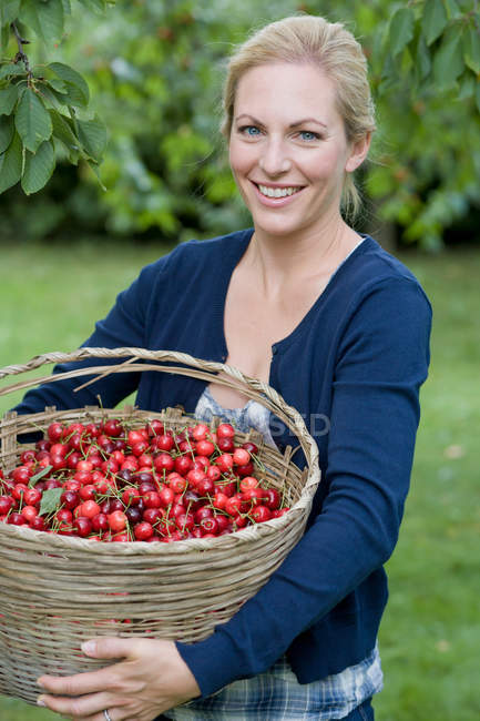 Woman carrying basket of cherries — Stock Photo