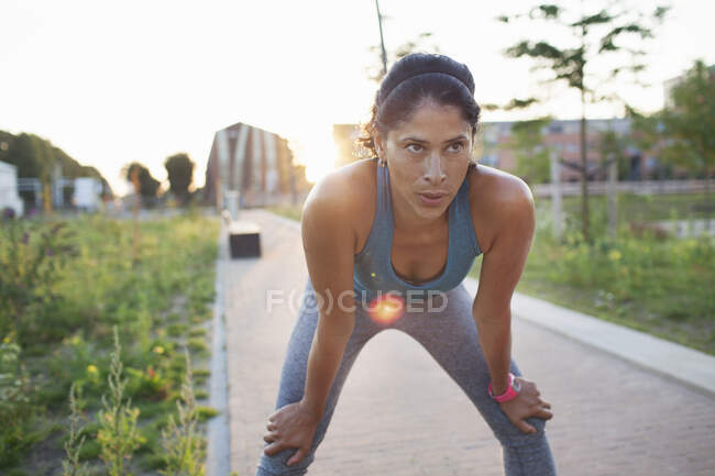Female runner taking a break on sidewalk — Stock Photo