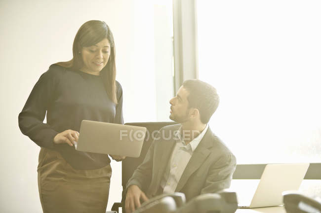 Колеги середнього бізнесу для дорослих обговорюють ноутбук в офісі — стокове фото