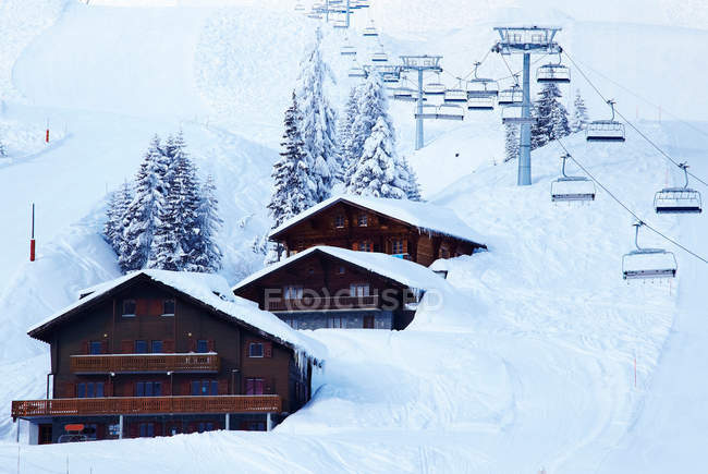 Лыжные подъемники над домиками в снежном дрейфе — стоковое фото