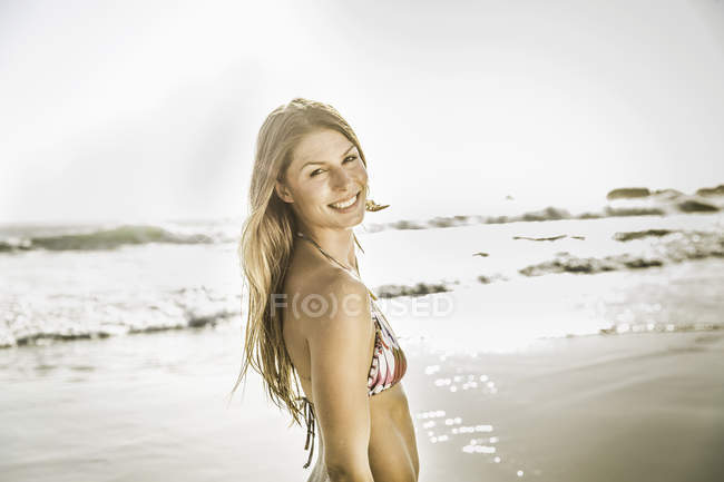 Portrait of woman wearing bikini top looking over her shoulder at beach, Cape Town, South Africa — Stock Photo