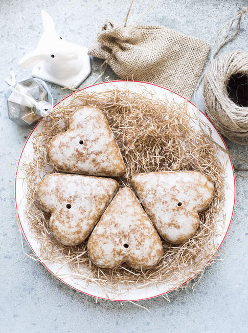 Top view of heart shaped gingerbread biscuits on straw covered plate — Stock Photo
