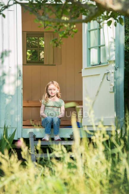 Menina sentada em degraus na porta — Fotografia de Stock