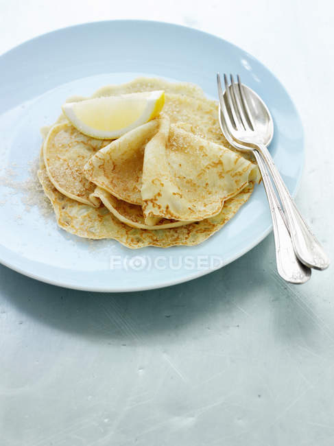 Primo piano di piatto di crepes con fetta di limone e posate — Foto stock