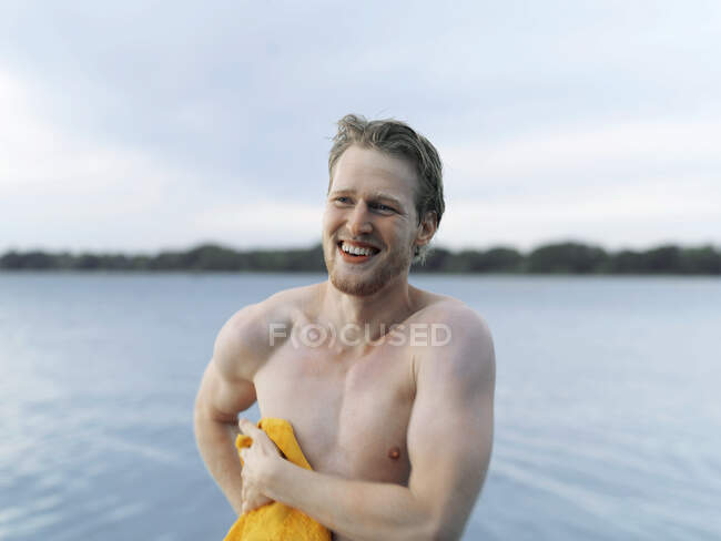 Nackter junger Mann, der mit Handtuch trocknet, lächelnd wegsieht, Kopenhagen, Dänemark — Stockfoto