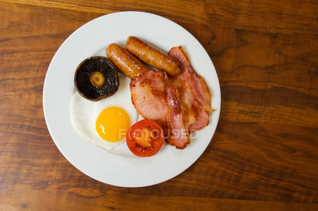 Assiette de petit déjeuner avec saucisses, bacon et oeuf — Photo de stock