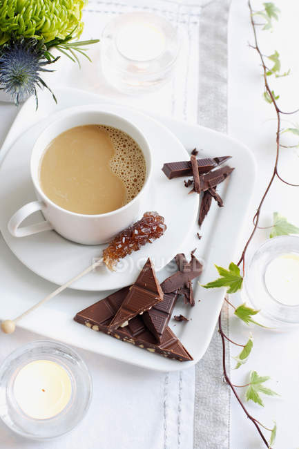 Tazza di caffè con pezzi di cioccolato sul tavolo — Foto stock