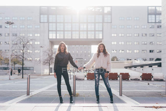 Retrato de irmãs gêmeas, na área urbana, lado a lado, de mãos dadas — Fotografia de Stock