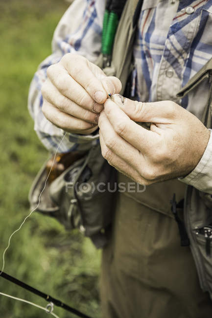 Vista recortada de las manos masculinas preparando la línea de pesca - foto de stock