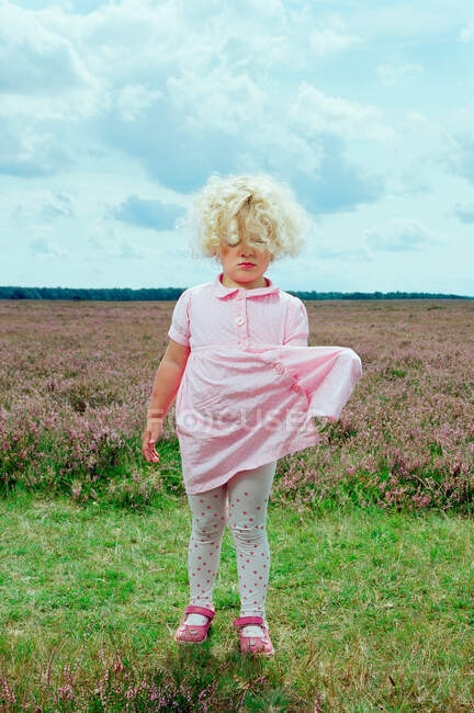 Girl pulling dress in field of flowers — Stock Photo