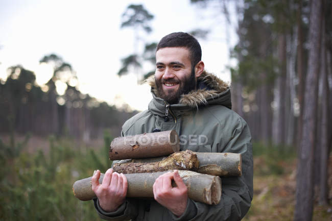 Молодий чоловік збирає колоди для багаття в лісі — стокове фото