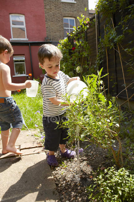 Niños regando plantas en el jardín - foto de stock