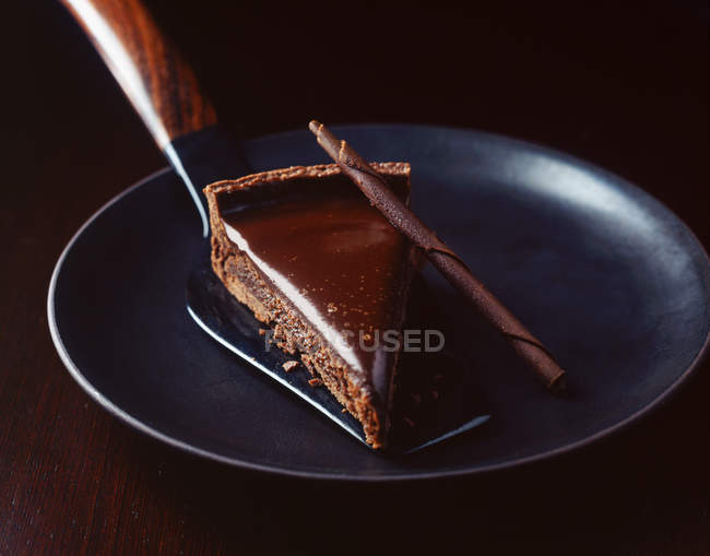 Slice of chocolate with cake server on plate — Stock Photo