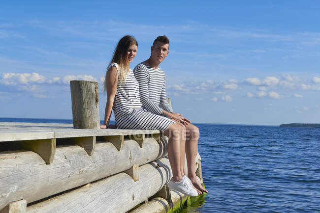 Молодая пара сидит на деревянном пирсе, расслабляется — стоковое фото