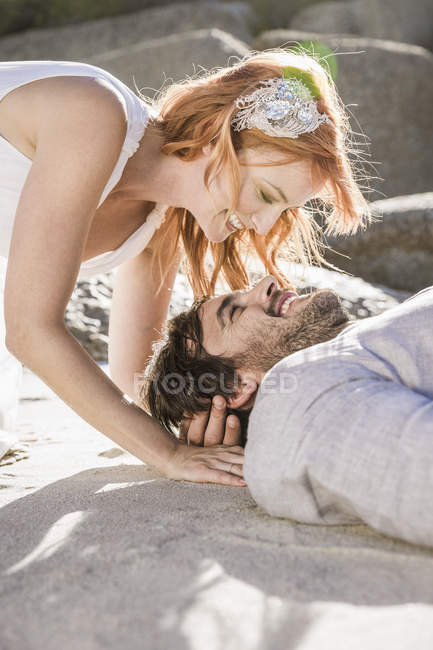 Cabeza y hombros de pareja acostada en la playa cara a cara sonriendo - foto de stock