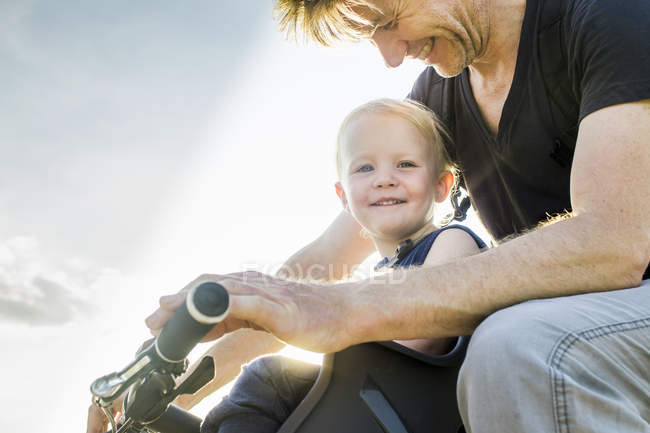 Father and baby daughter riding bike together — Stock Photo