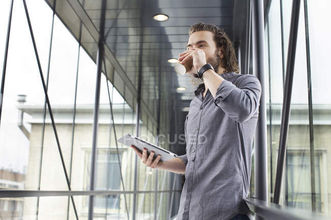 Homme avec tablette numérique sur pause café dans un bâtiment moderne — Photo de stock