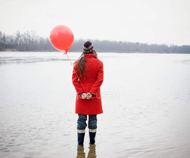 Giovane donna in fiume con palloncino rosso in mano — Foto stock