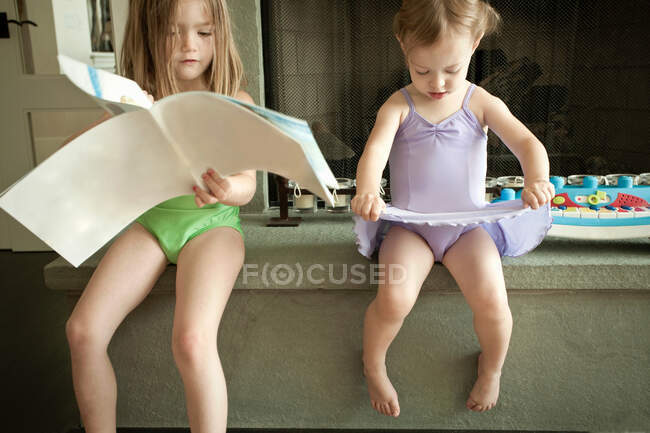 Girls in swimsuits sitting on counter — Stock Photo