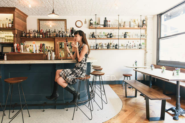 Молода жінка одягає помаду в коктейль-барі — стокове фото