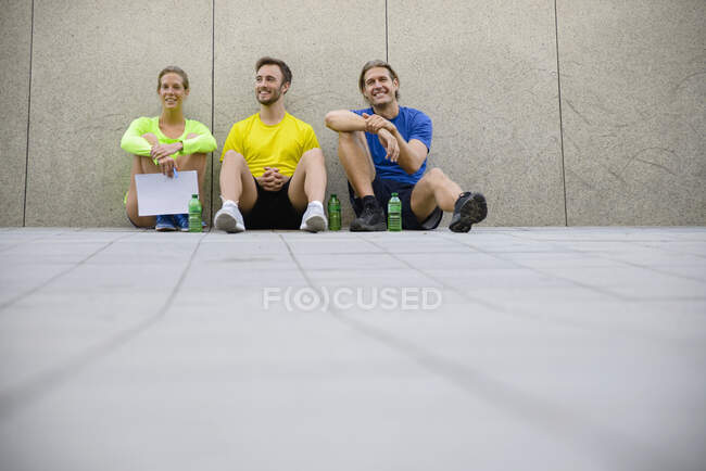 Троє друзів сидять на підлозі в спортивному одязі — стокове фото