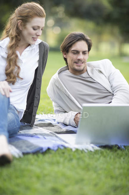 Uomo d'affari e collega di sesso femminile guardando computer portatile nel parco — Foto stock